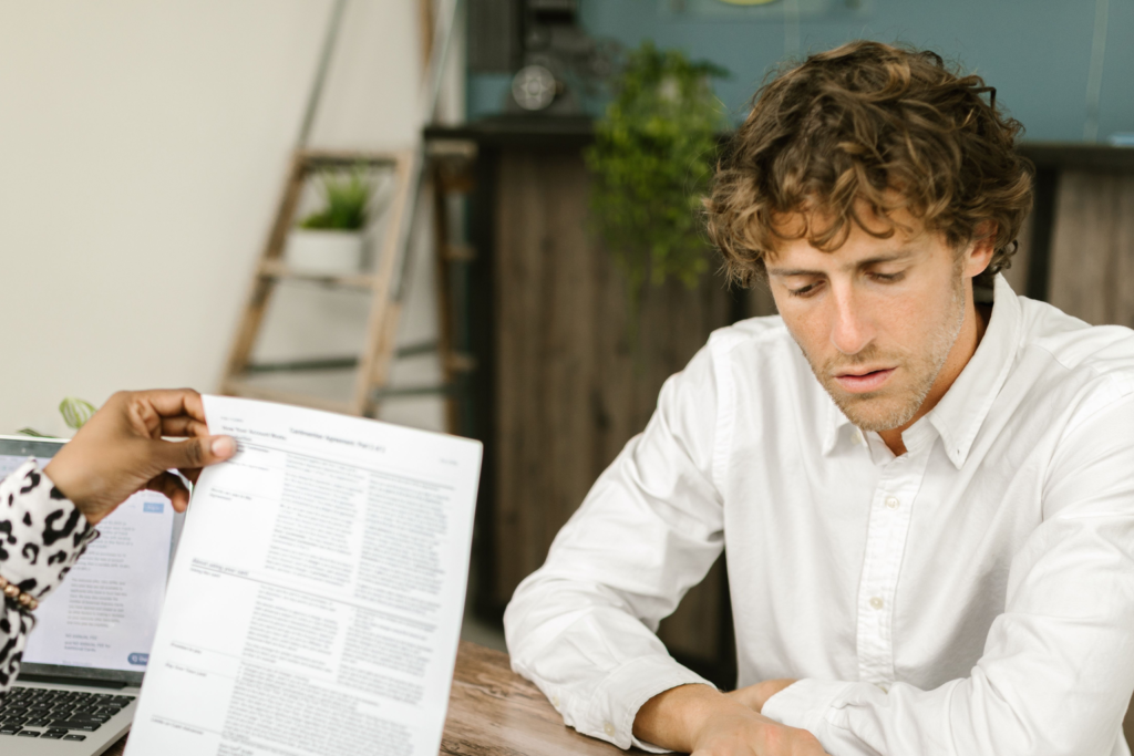 Twee collega's nemen aan tafel de documenten door die bij ISO 27001 in het MKB komen kijken